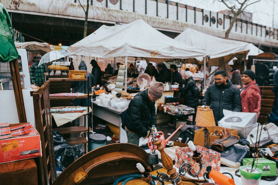 A red double-decker bus approaching on a busy street with several pedestrians nearby, passing in front of the iconic Elizabeth Tower, commonly known as Big Ben, which features a large clock face on it